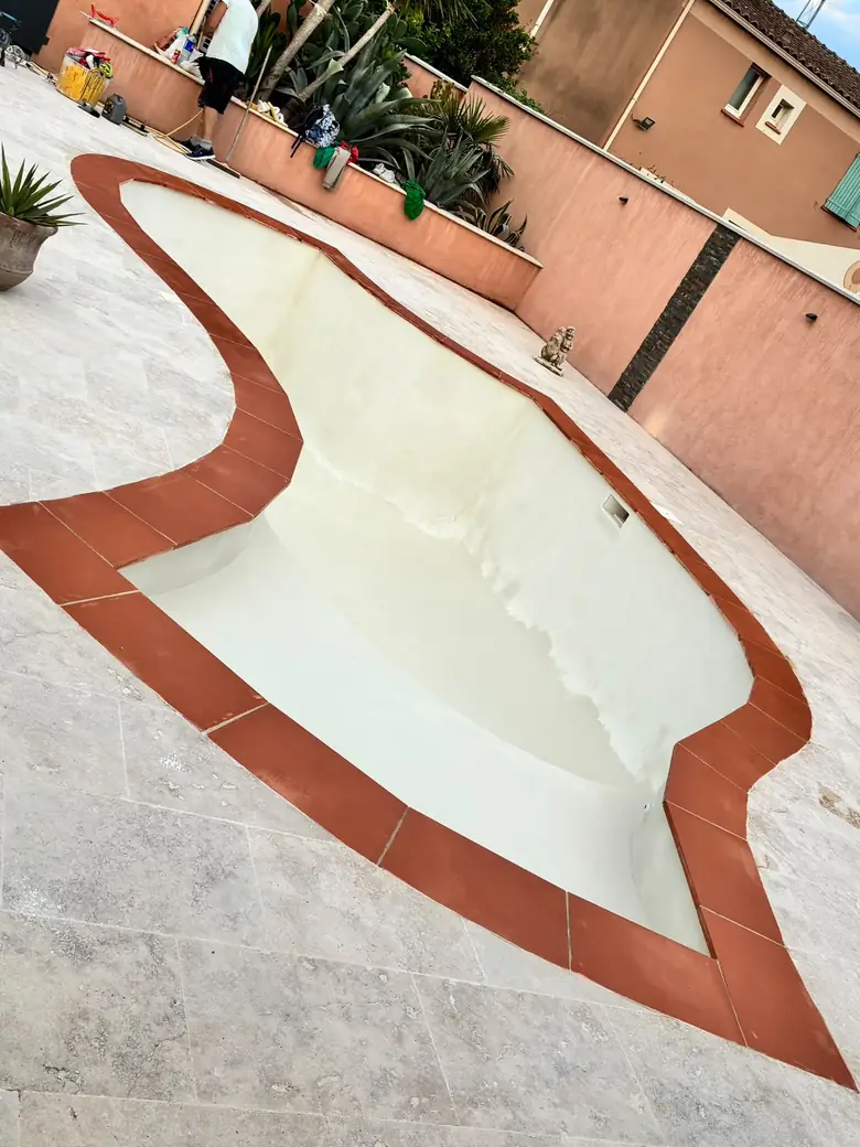 Piscine de forme libre, margelles en terre cuite et dallage neuf.