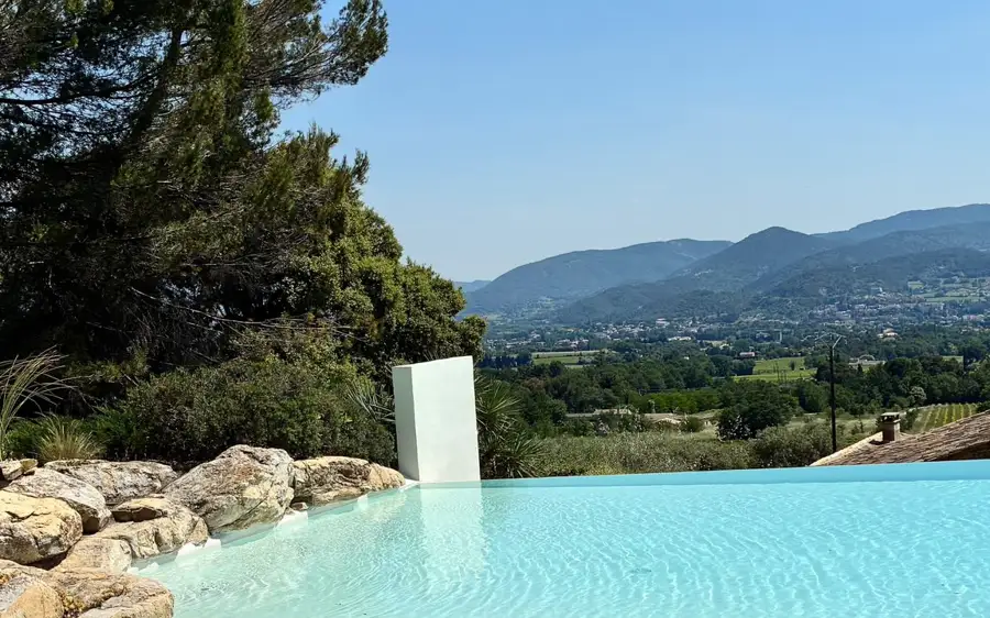 Piscine à débordement avec plage immergée, face aux collines.