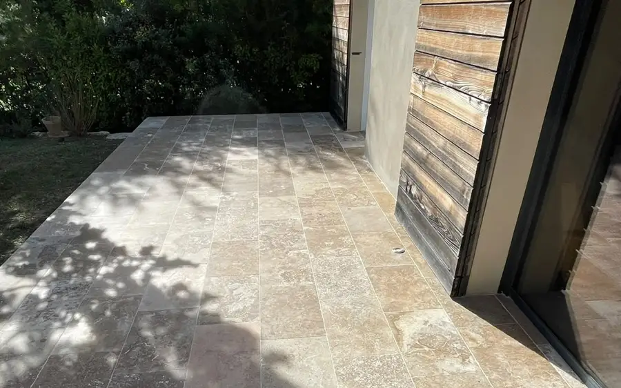 Terrasse dallée en pierre naturelle le long de la maison.